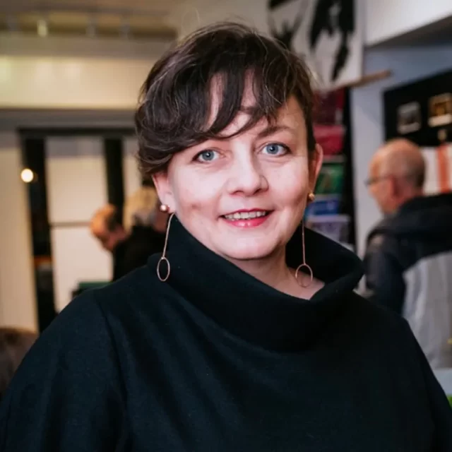 A photo of a brunette woman wearing a black sweater.