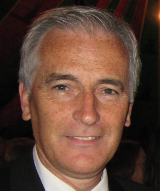 A closeup of a man's face, grey hair.